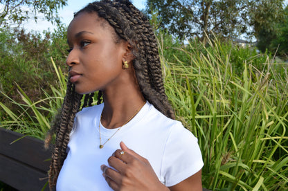 Thin gold chain adjustable ring featuring a white oval gem, worn on a girl with The Aerinas Coil Earrings and The Afsanas Heart Necklace