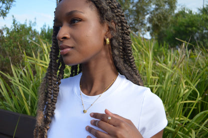 Gold chain necklace with a small gold heart-shaped pendant and small gold spheres evenly along the chain, worn on a girl with The Aerinas Coil Earrings and The Faridas Adjustable Ring