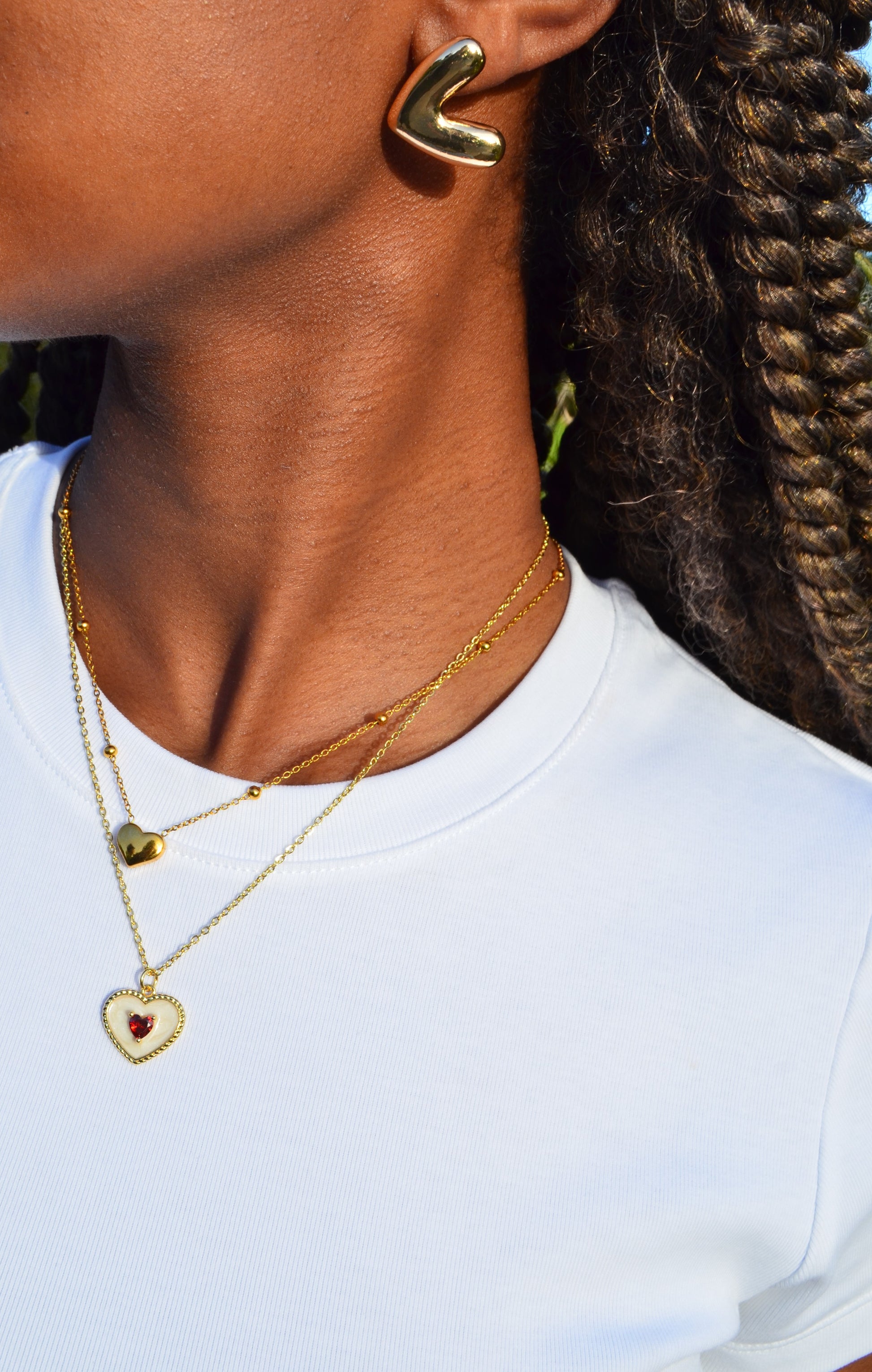 Thick heart-shaped gold stud earrings worn on a girl with the Queen of Hearts Necklace and The Afsanas Heart Necklace