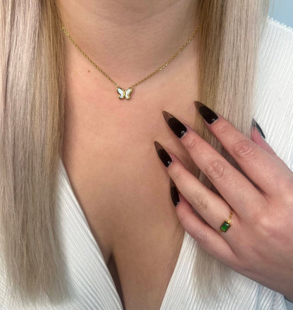 Adjustable thin gold ring with a gold sphere adjuster featuring rectangular green gem and The Nisas Butterfly Necklace shown on a girl