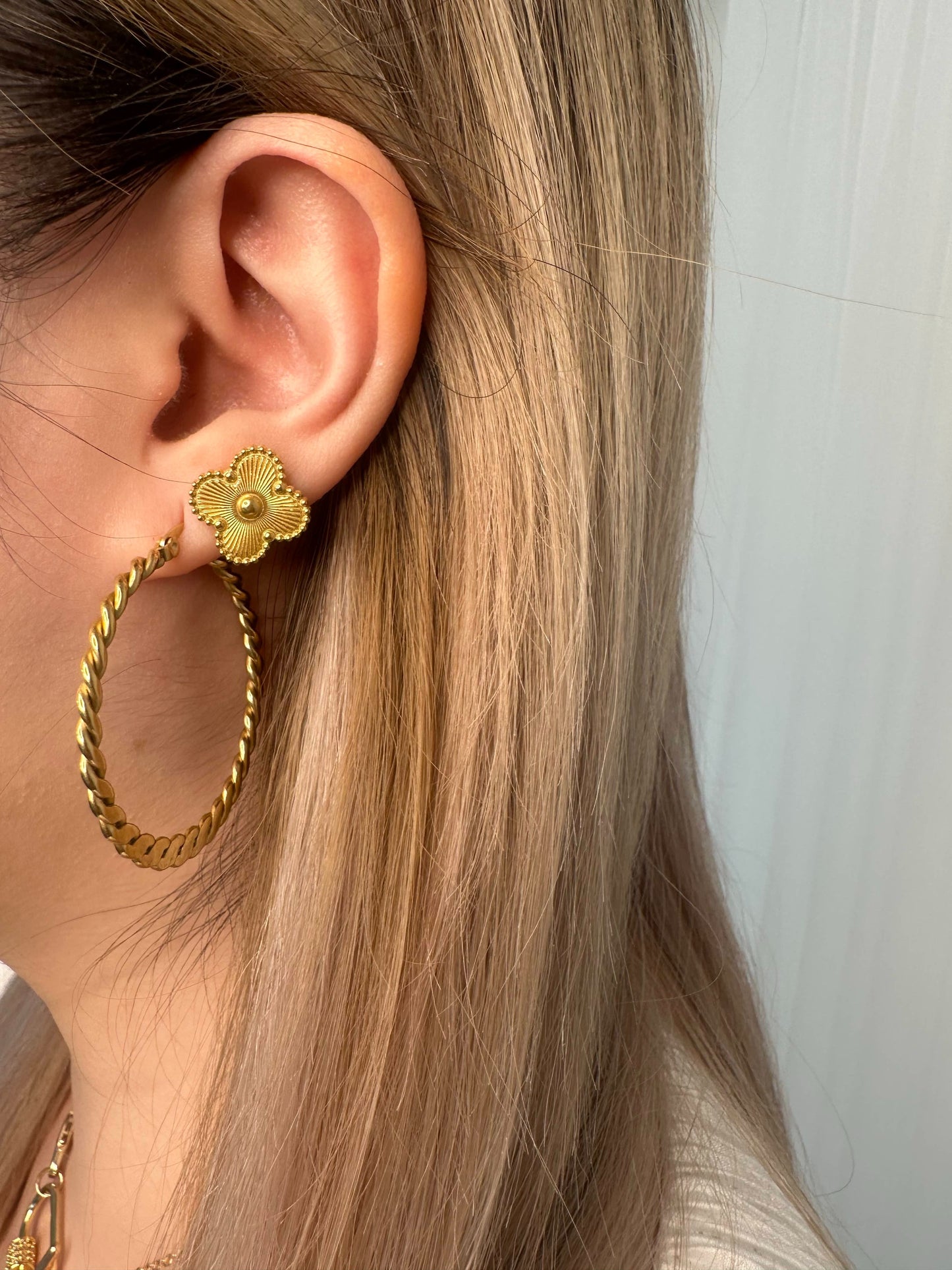 Thin gold twist large hoop earrings shown on a girl