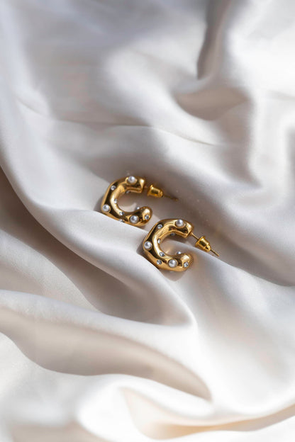 Gold stud earrings with a thick abstract design, featuring small pearl polka dots