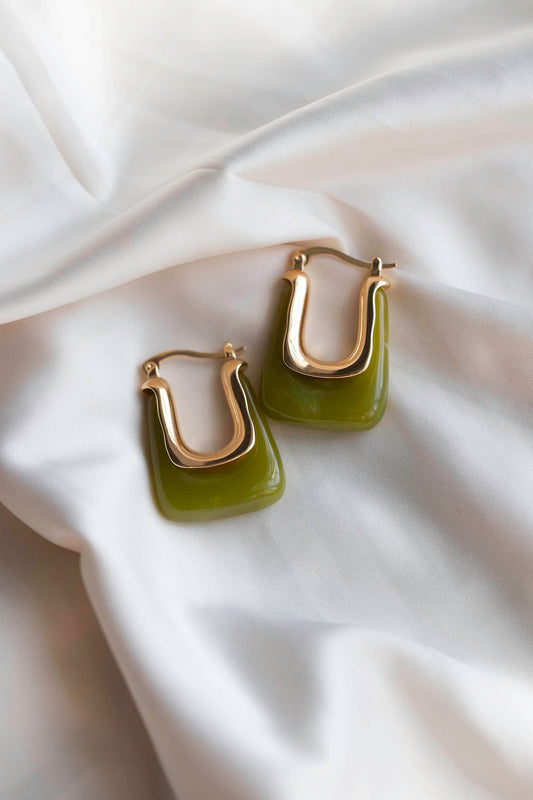 Green rectangular earrings with gold hardware, displayed on silk